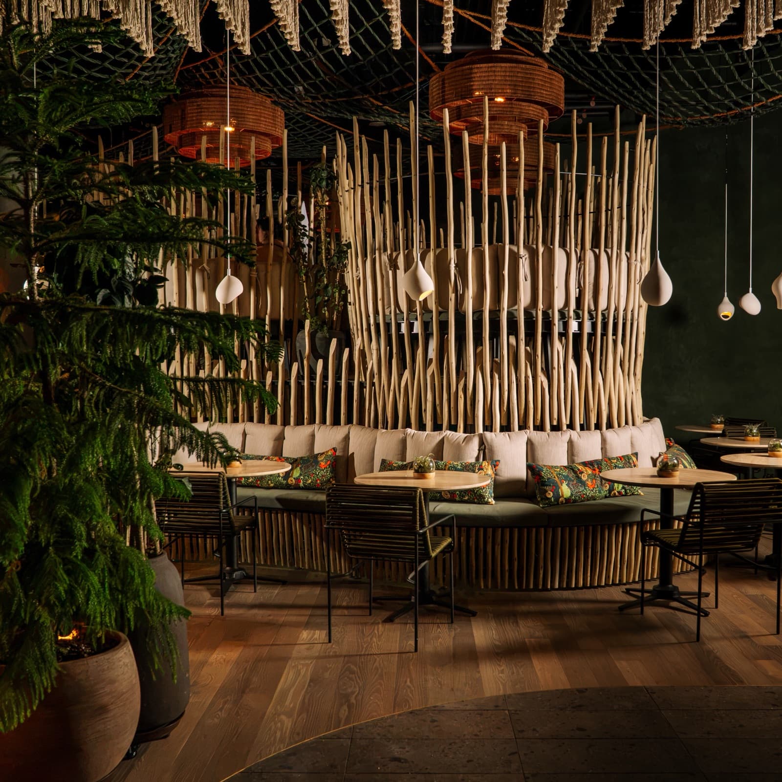 Curved banquette seating beneath the driftwood canopy at Forbidden Fruit