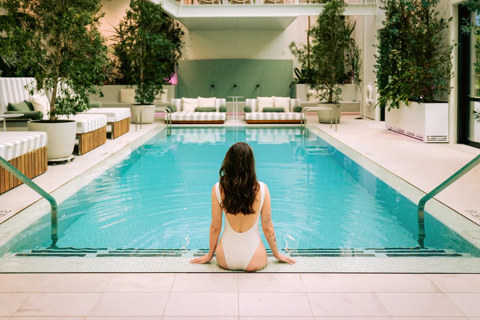 A guest resting at the edge of the Conservatory pool surrounded by greenery