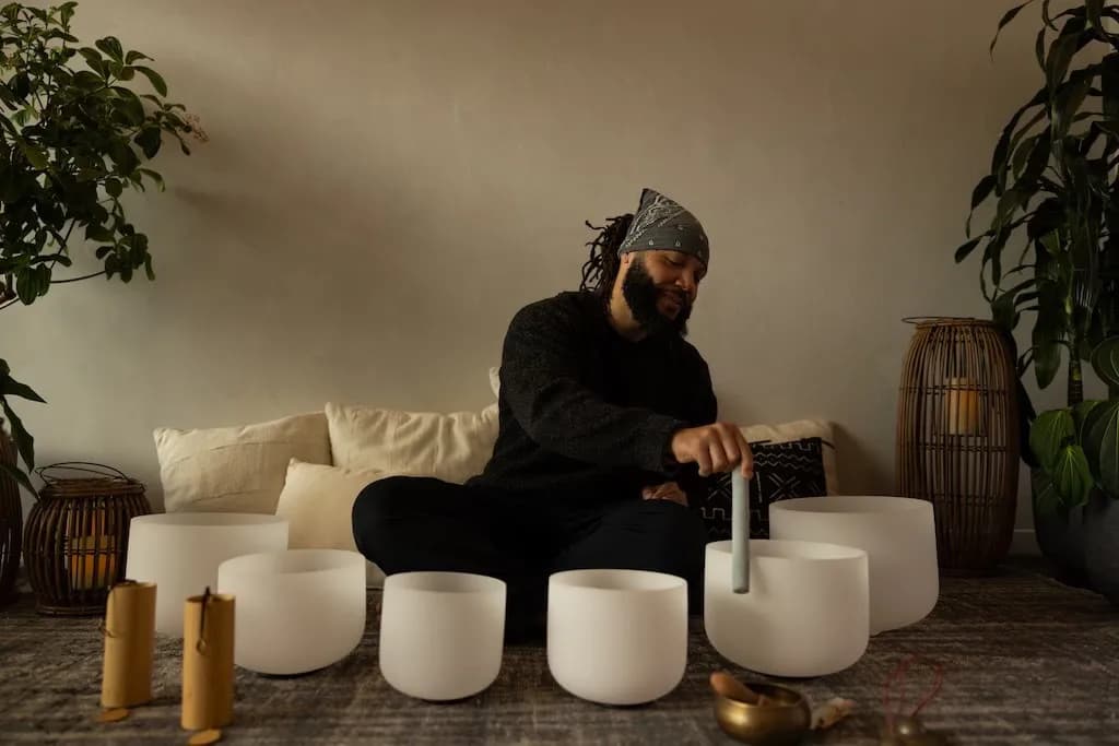 A sound practitioner playing crystal singing bowls